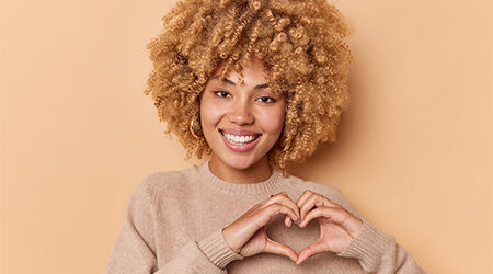 Girl with short curly hair showing heart hands