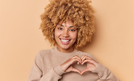 Girl with short curly hair showing heart hands